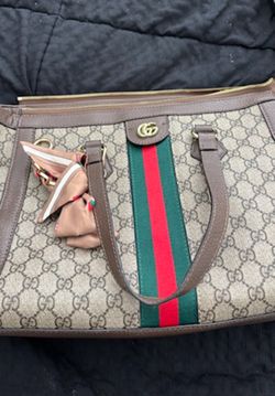 Gucci Medium Ophidia GG Tote crafted in beige GG Supreme coated canvas with brown leather trim and a green and red Web stripe.