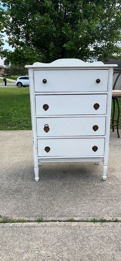This white dresser features four drawers and distinct distressed detailing along the https://offerup.com/redirect/?o=ZWRnZXMuU3R5bGU=: The piece appea
