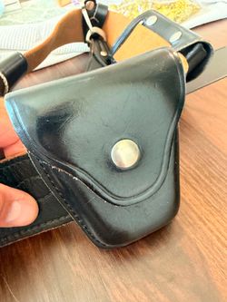 Black leather duty belt setup equipped with a double-pouch attachment and a cylindrical holster or flashlight holder