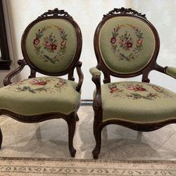 A pair of antique Victorian carved wood armchairs with floral needlepoint upholstery.