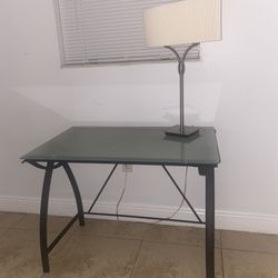 glass desk with lamp and a mattress with its base