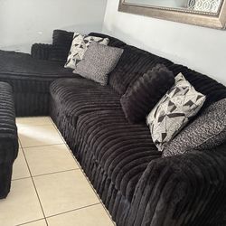 Black ribbed sectional with ottoman and pillows