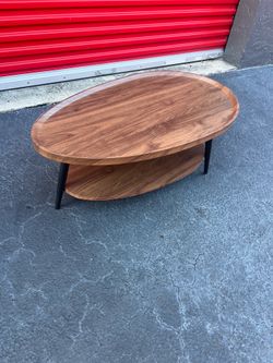 Saint Mossi mid-century modern coffee table features a distinctive teardrop-shaped top with raised edges and tapered black
