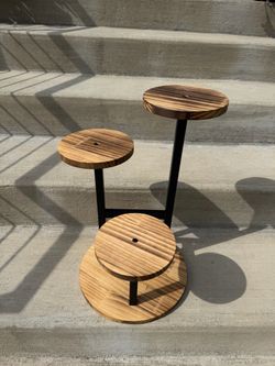 Multi-tiered plant stand features a black metal frame with four round wooden trays. 🪴