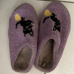Purple slippers with a black cat on it