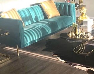 Green velvet loveseat and cowhide rug