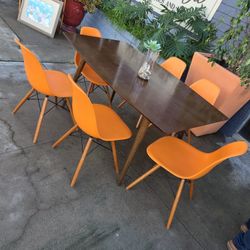 Eames Wood dining table set with orange Eiffel chairs.