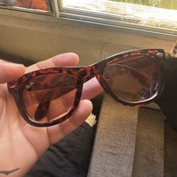 These sunglasses are Ray-Ban Original Wayfarer Classic sunglasses, featuring a tortoise frame and brown lenses