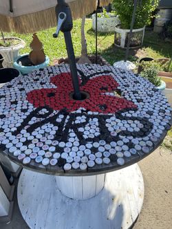 Rustic shabby outdoor spool wood table with bottle cap nailed on top- 39.5 inches wide/ 32 inches high holds umbrella in middle  - umbrella not includ