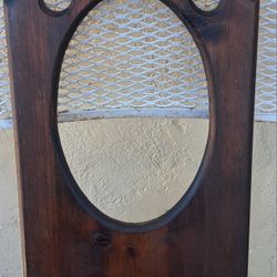 antique-style wooden wall mirror with a small shelf. 
