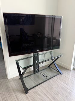 Samsung 55” LED TV with glass and black metal TV stand.