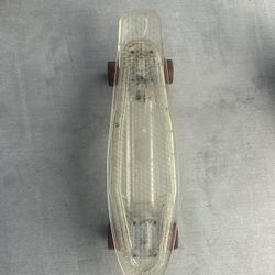 The skateboard shown is a clear plastic cruiser skateboard, often referred to as a "Penny board".