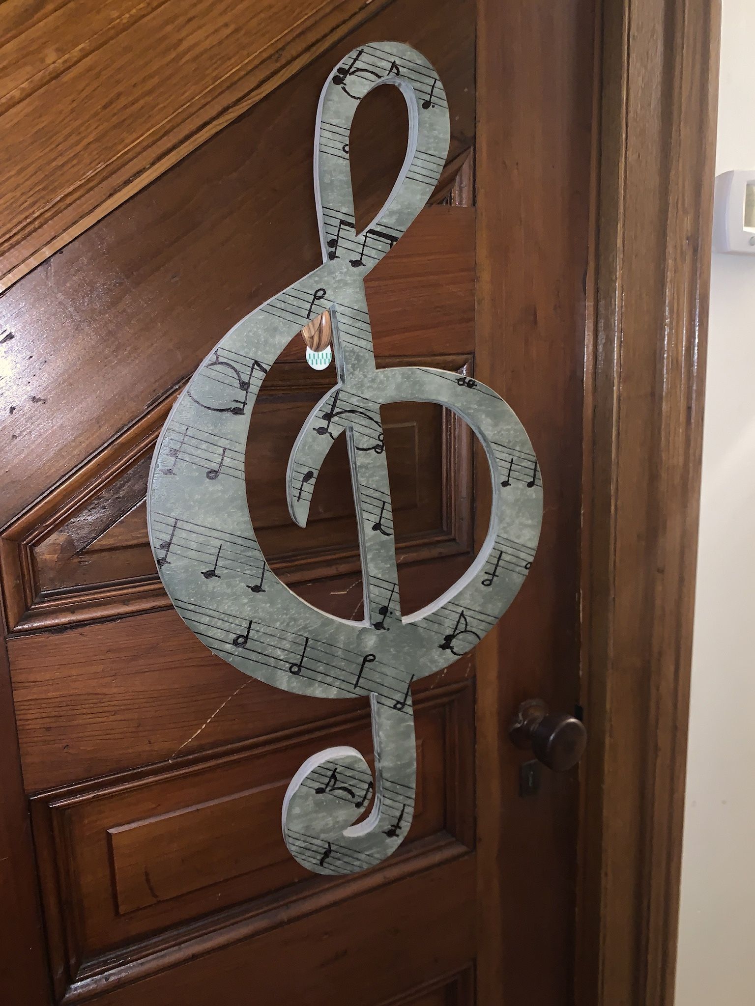 Wooden Gclif Music note with the sheet music to faithfully by journey on it