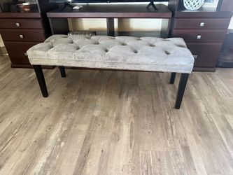 Elegant gray upholstered bench with tufted design and black legs.