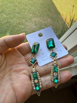 Make a bold statement with these stunning, long dangle earrings. Featuring vibrant emerald-green geometric crystals accented with shimmering clear rhi