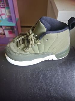 This is a toddler-sized Nike Air Jordan 12 Retro sneaker in an olive green and metallic gold colorway.