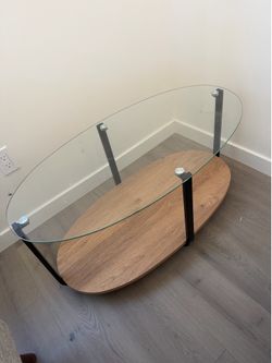Modern Oval Glass Coffee Table - $60  Modern oval coffee table in great condition. Features a tempered glass top, sturdy black metal frame, and wood-l