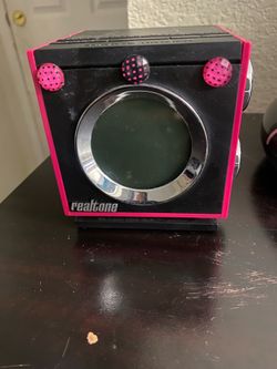 This is a Realtone RT205 retro AM/FM dual alarm clock radio featuring a distinctive black cube design with bright pink accents.