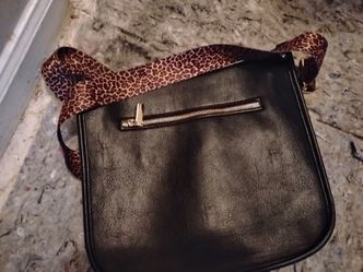 Black purse with a cheetah belt on it