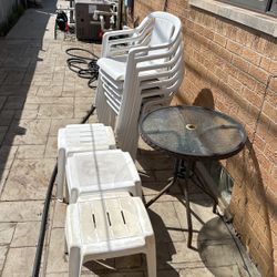 7  Grosfillex Plastic Chairs , 3 Plastic Tables ,  And One Outdoor Round Temperglass Coffee Table 