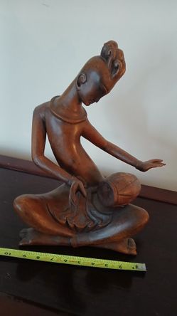hand-carved wooden statue of a Thai dancer playing a drum