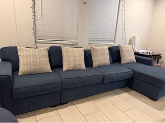 A large sectional sofa with a chaise with 4 pillows.