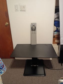 black sit-stand desk converter, which appears to resemble a Humanscale QuickStand
