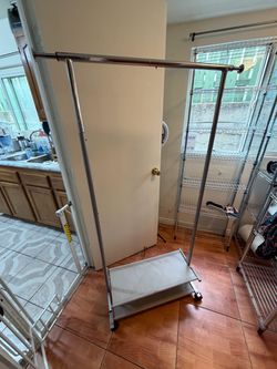 metal single-rail garment rack with a fabric bottom shelf and caster wheels