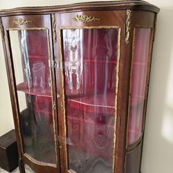 A Louis XV-style antique display cabinet with a curved front and gilt-bronze details.