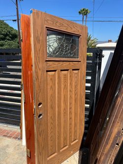 Sturdy wood exterior door has a medium brown oak finish and a craftsman-style design with three vertical panels. This door features a rectangular deco