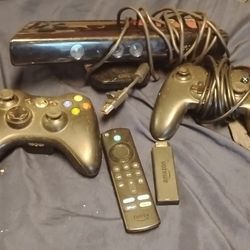 The image shows a bundle of an Xbox 360 console and accessories. 
The bundle includes the black Xbox 360 S or E console model, two black wireless cont