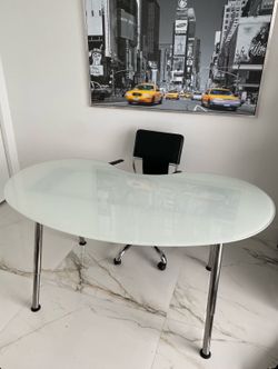 Modern kidney-shaped desk with a frosted glass top and adjustable chrome legs.