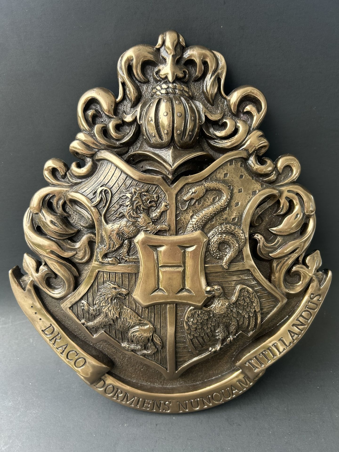 The Harry Potter Hogwarts School Crest WALL ART Wall Hanging is a collectible piece inspired by the iconic Hogwarts School from the Harry Potter fran