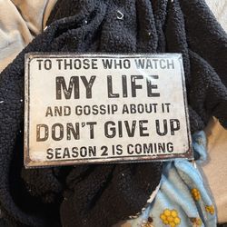 The image features a rustic metal wall sign with text aimed at gossipers.