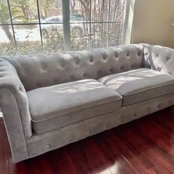 Elegant gray tufted sofa in excellent condition.