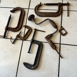 antique metal C-clamps and a hand-crank drill with a worn rusty patina