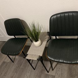 Chairs with dark green upholstery and a small central side table.