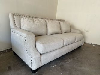 Light beige 3-seat sofa with textured upholstery, nailhead trim, and black wood legs.**Free Delivery** 🚚