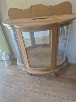 vintage curved glass oak curio cabinet with a mirrored back and a lockable door, often used for displaying collectibles.