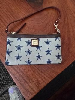 Fashion and convenience are found in the Dooney & Bourke Dallas Cowboys large wristlet. This wristlet is the perfect size for keeping your essentials 