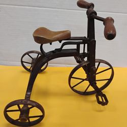 Vintage miniature metal and wood decorative tricycle, often used as a collectible item.