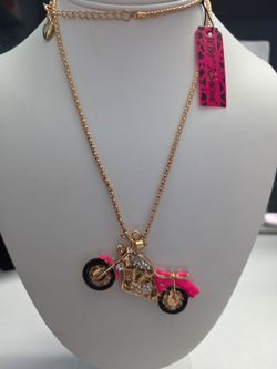 Betsey Johnson statement necklace featuring a dimensional motorcycle pendant in a gold-tone finish.