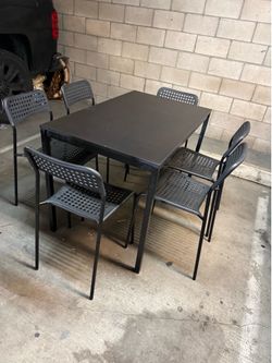 Black dining table with metal frame and six stackable chairs 43 1/2 x 26 1/2 x 29