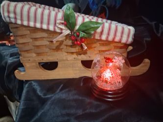 A wicker Christmas sleigh and Santa Claus snow globe with LED lights