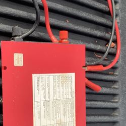 Red power inverter with attached cables.