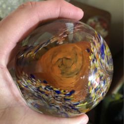 Vintage clear glass paperweight with orange flower and colorful glass surrounding it