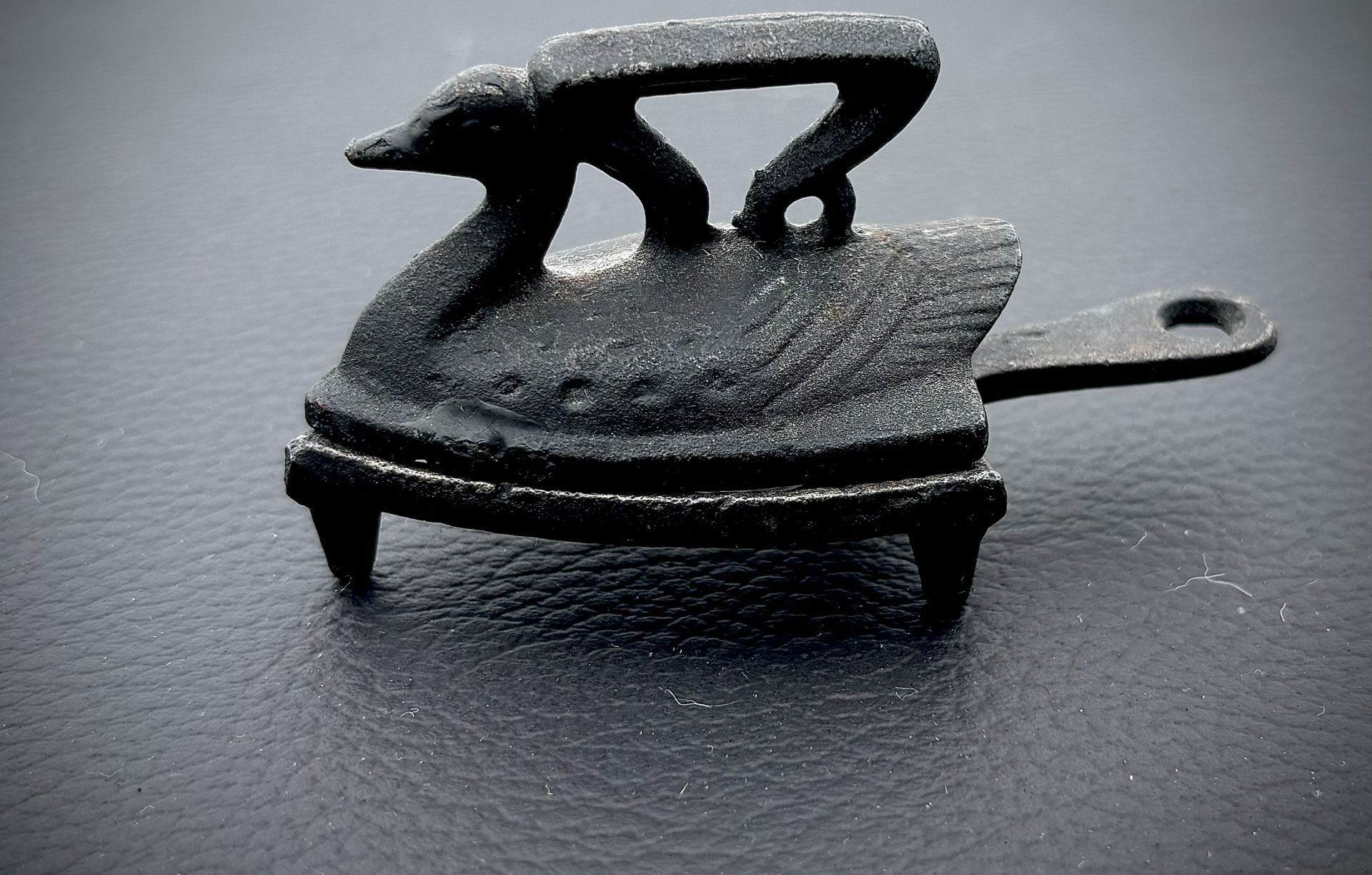 vintage miniature cast iron "sad iron" in the shape of a swan/duck accompanied by a matching trivet