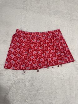 Playful mini skirt with a vibrant pink and red heart-and-cherry print. Lightweight, flared silhouette that moves with you. Decorative removable metal