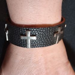 Black Leather Bracelet With Silver Crosses Going Around It 