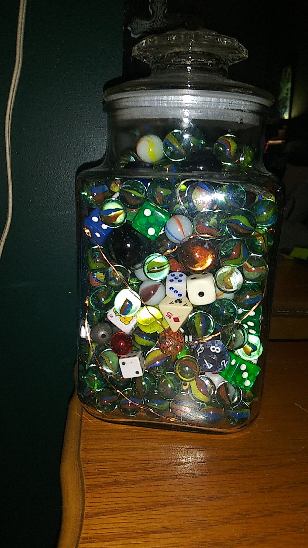 Glass jar full of various sized and colored marbles & various types of dice with copper wire battery powered lights